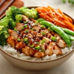 Bowl of teriyaki chicken, rice, and vegetables drizzled with teriyaki sauce.